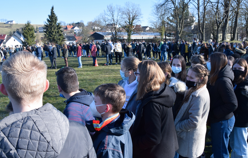 Schülerinnen und Schüler setzen mit ihren Lehrern ein Zeichen für den Frieden. Im Vordergrund sieht man die Siebtklässler.