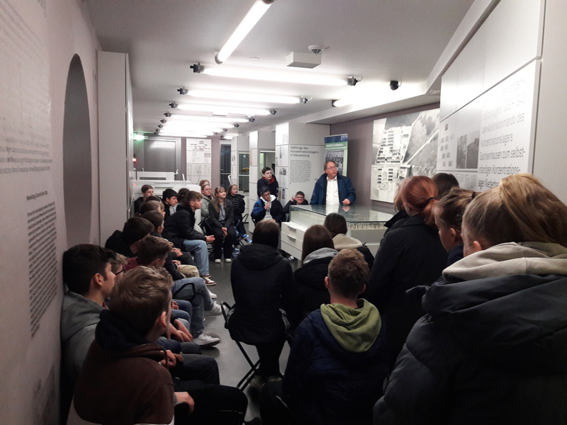Historiker und Museumspädagoge Norbert Ellermann erläutert den Schülerinnen und Schülern der Klasse 9a in der historischen Ausstellung die Geschichte des damaligen Konzentrationslagers Niederhagen/Wewelsburg.
